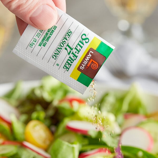 A hand holding a Lawry's Salt-Free 17 Seasoning packet.