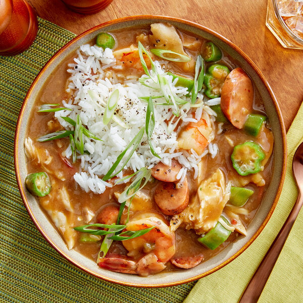 A bowl of gumbo with rice and shrimp and vegetables.