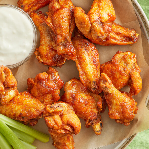 A plate of fried chicken wings with Lawry's Mango Habanero seasoning mix and a side of celery and ranch dressing.