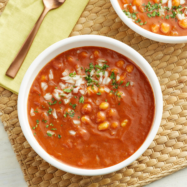 A bowl of corn soup with McCormick Moroccan Seasoning and green garnish next to a spoon.