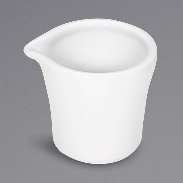 A Bauscher bright white porcelain creamer with a small liquid inside.
