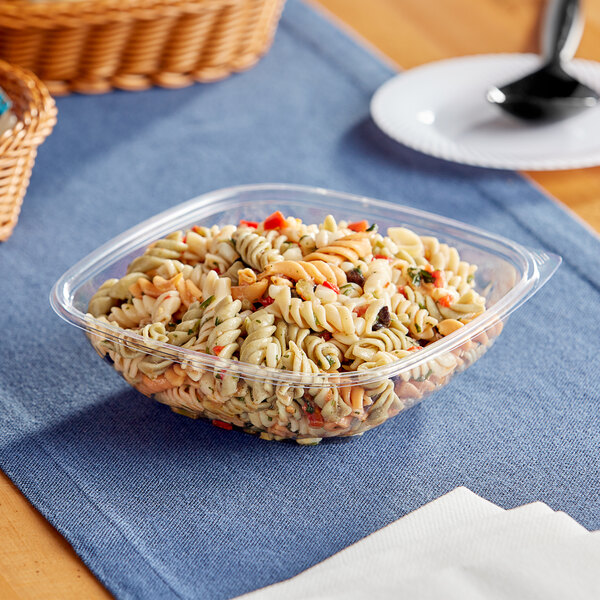 A Visions clear plastic bowl filled with pasta salad on a table.