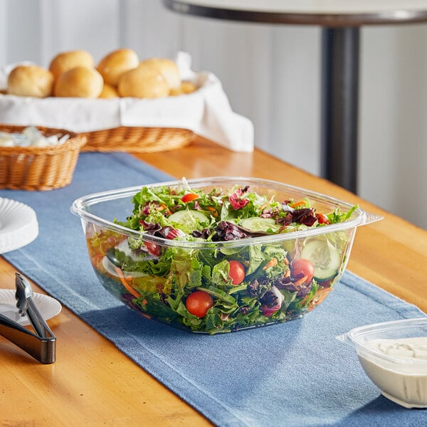 A salad in a clear plastic bowl on a table.