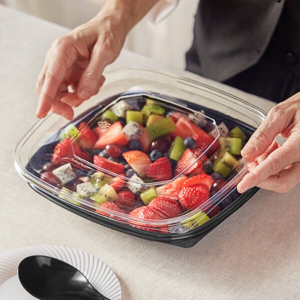 a hand reaching for a bowl of fruit