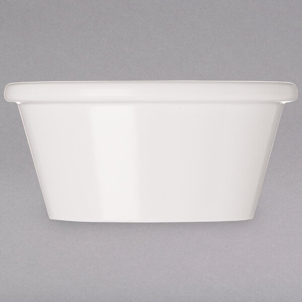 An ivory melamine oval ramekin on a gray surface.