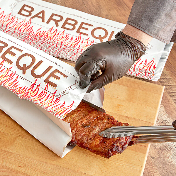 A person cutting meat in a foil bag with a knife.