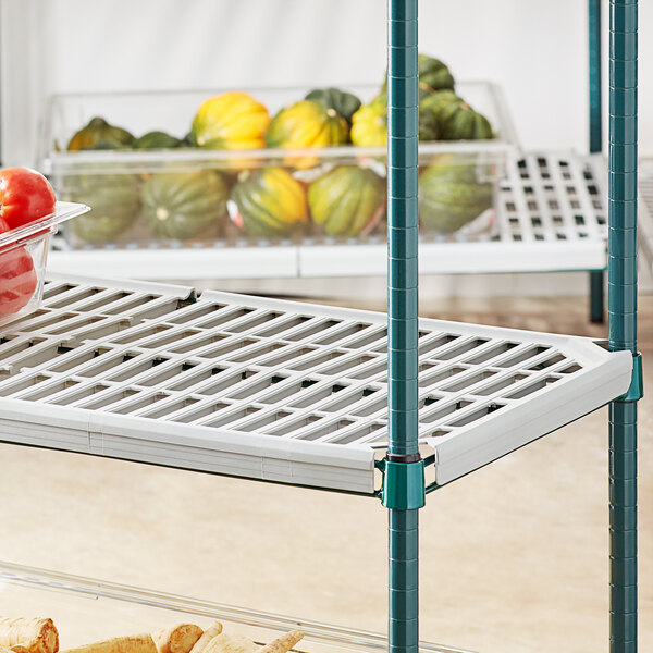 A Regency green wire shelf with vegetables on it.