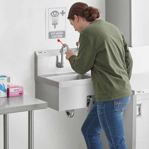 A woman using a knee operated hand sink.