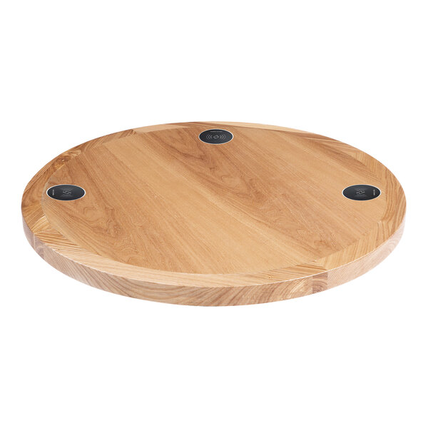 A BFM Seating round natural ash veneer wood table top with 3 wireless chargers.