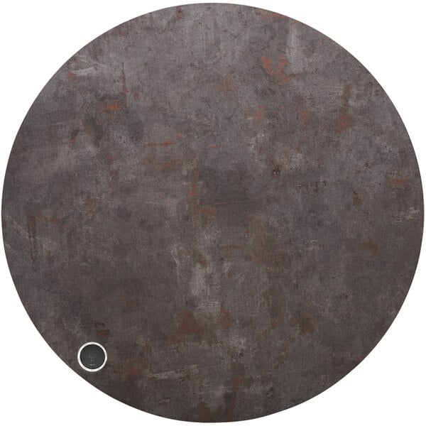 A BFM Seating Relic round rustic copper melamine table top with a wireless charger on it.