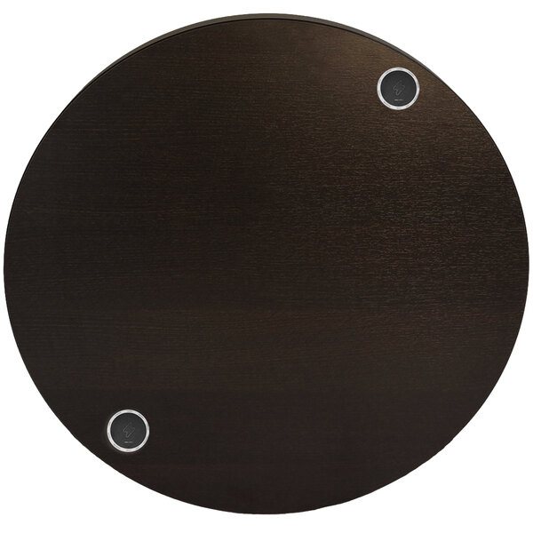 A round espresso table top with two wireless chargers.