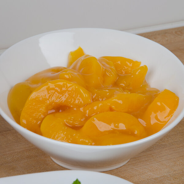 A bowl of peaches in a sauce.