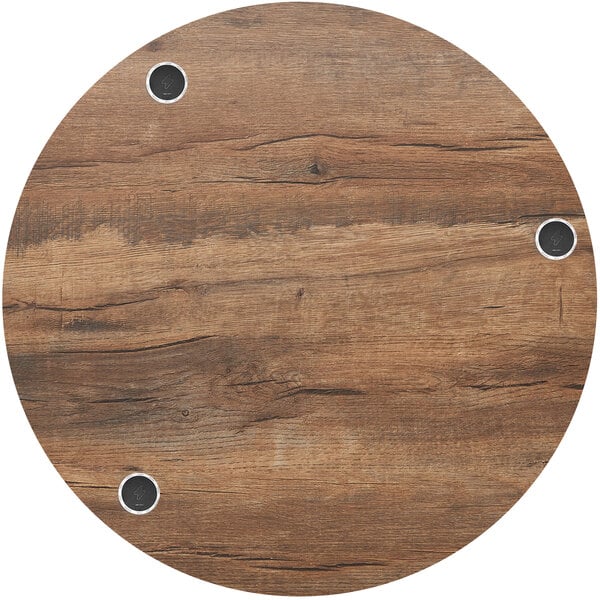 A BFM Seating Relic round knotty pine table top with wireless chargers.