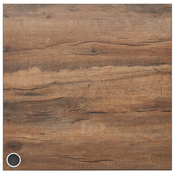 A wood surface with a metal circular charging panel in the middle.