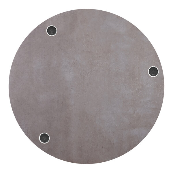 A BFM Seating Midtown round tabletop with wireless chargers and a textured concrete finish with holes for chargers.