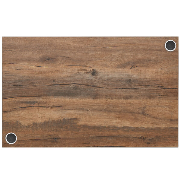 A wood table top with a knotty pine wood grained surface and holes for wireless chargers.