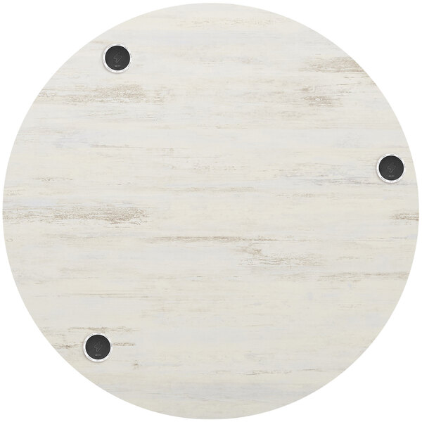 A white circular BFM Seating Relic table top with black circles and 3 wireless chargers.