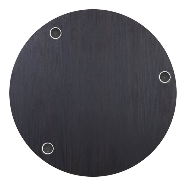 A circular espresso tabletop with holes for wireless chargers.