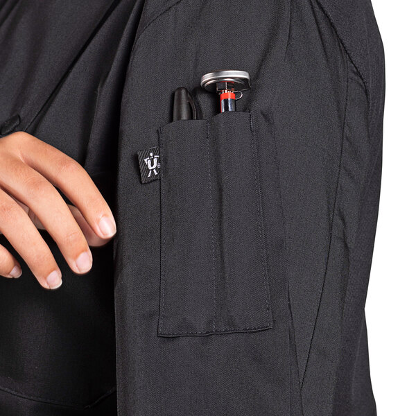 A woman's Uncommon Chef Tempest Pro Vent long sleeve chef coat with pockets, one holding a pen.