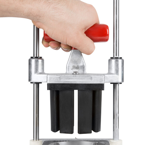 A hand using a Vollrath Redco InstaCut 4-8 Wedge Push Block with a red handle to cut a piece of paper.