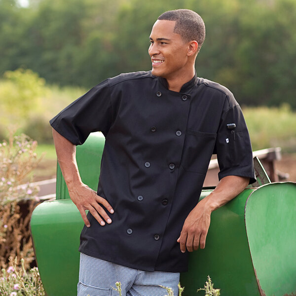 A man wearing a black Uncommon Chef Montego Pro Vent chef coat with a mesh back.
