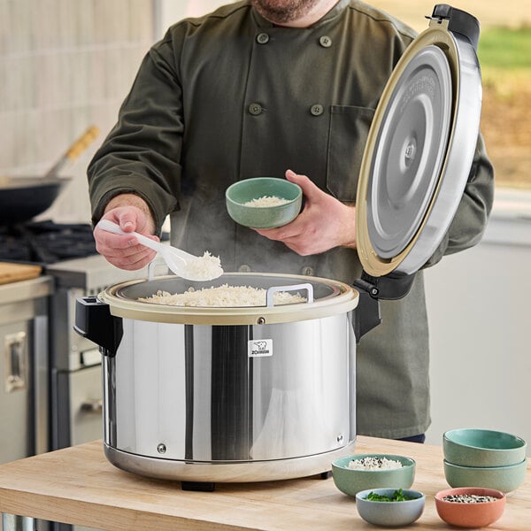 A man using a Zojirushi commercial rice warmer to cook rice in a large pot.