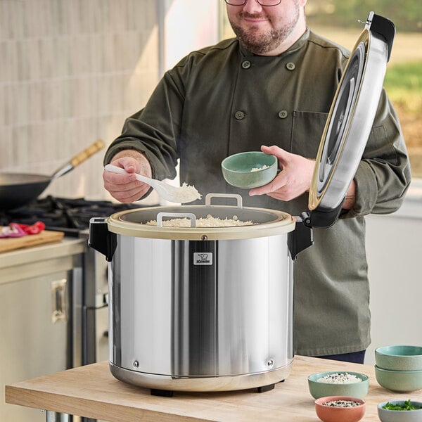 A man in a chef's uniform cooking rice in a large Zojirushi rice pot.