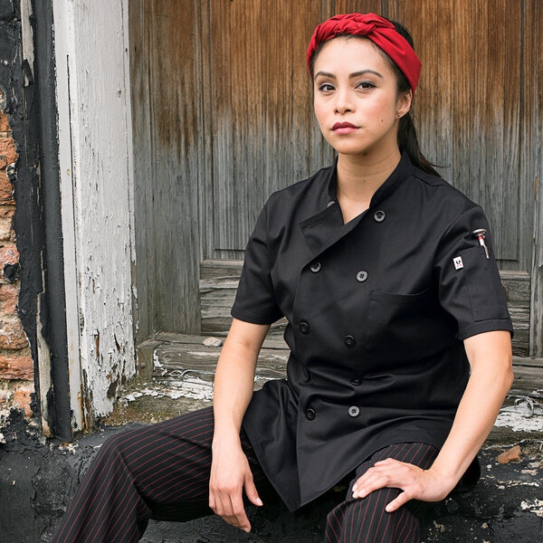a woman wearing a black coat and red headband sitting on a wooden door