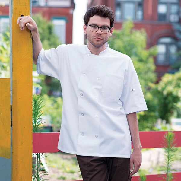 A man wearing a white Uncommon Chef Montego Pro Vent chef coat with mesh back.