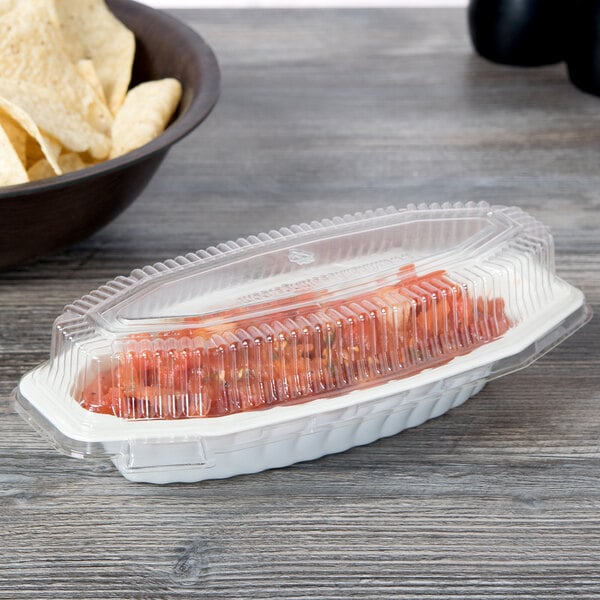 A Fineline plastic container with a clear lid filled with potato chips next to a bowl of chips.