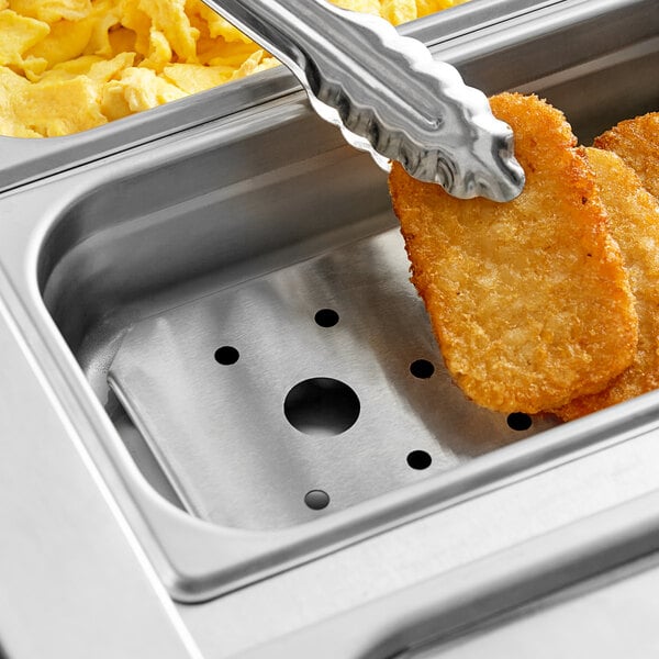 A stainless steel steam table pan with food in it on a hotel buffet counter.