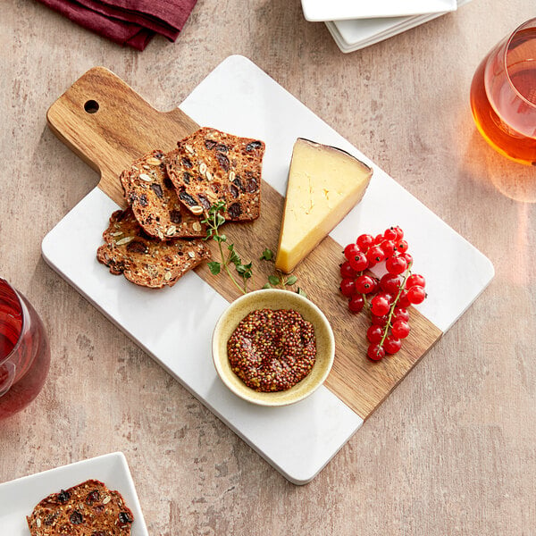 An Acopa acacia wood and marble serving board with cheese and crackers on it.