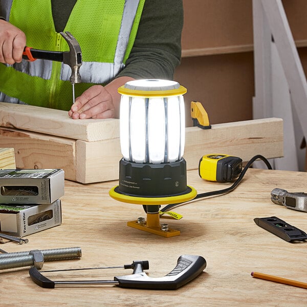 A man working with a Lind Equipment Beacon360 Blaze LED Portable Area Light on a table.
