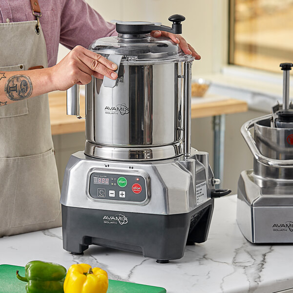 A man using an AvaMix stainless steel bowl and motor base to prepare food in a commercial kitchen.