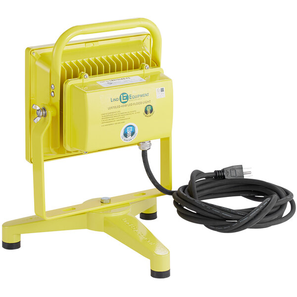 A yellow Lind Equipment LED floodlight on a floor stand with a cord.