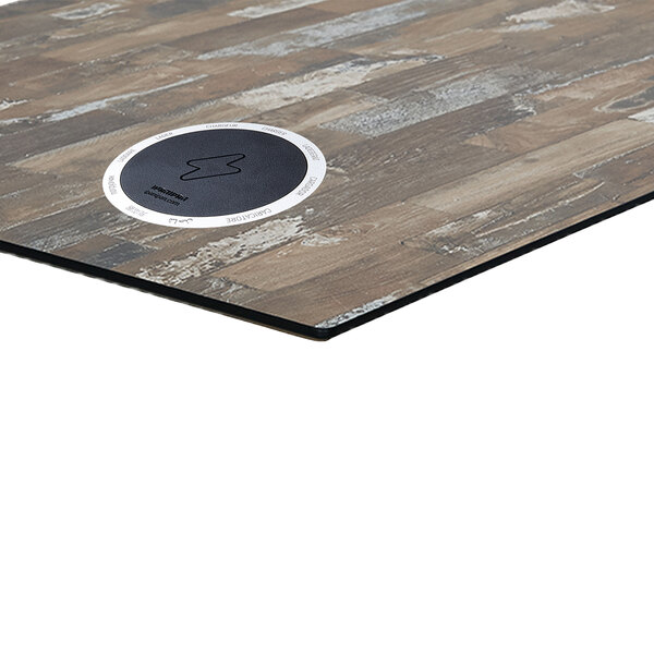 A BFM Seating wood table top with wireless chargers on a wood surface.