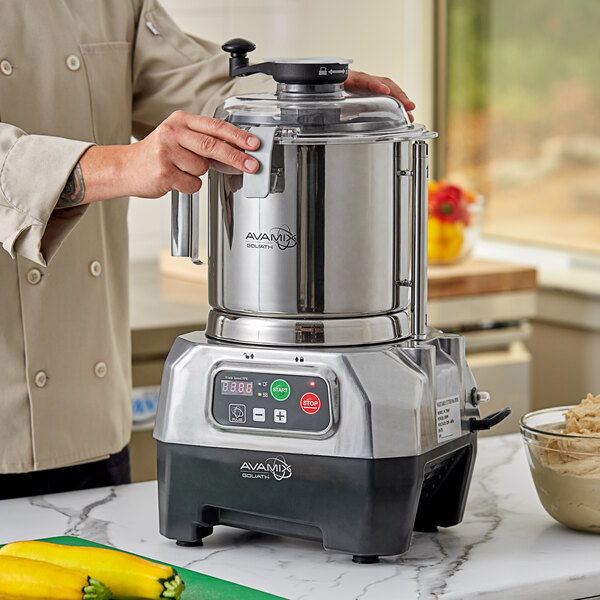 A person using an AvaMix stainless steel bowl on a food processor.