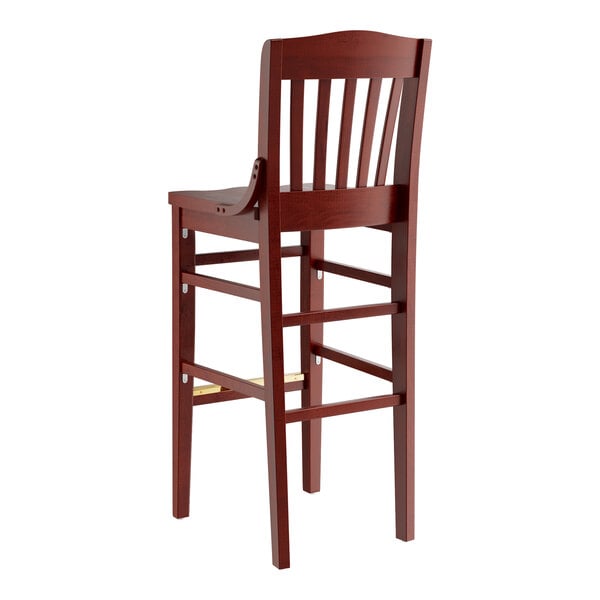 A Lancaster Table & Seating mahogany wood school house bar stool with a backrest.