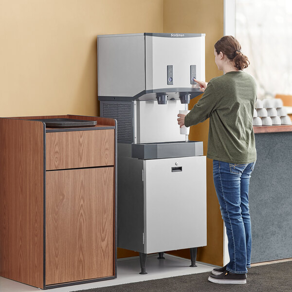 A woman pouring a drink into a Scotsman Meridian ice and water dispenser.