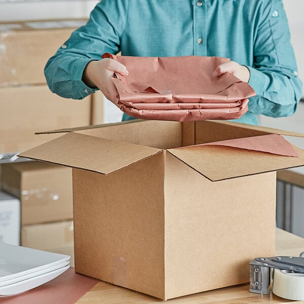 A man opening a box with a stack of pink Lavex void fill paper.