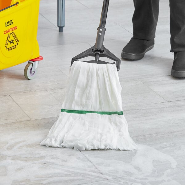 A person using a Lavex white microfiber wet mop with a 1" headband to clean a floor.