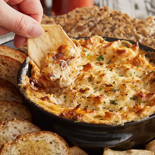 A person holding a cracker with Handy Lump Crab Meat dip.