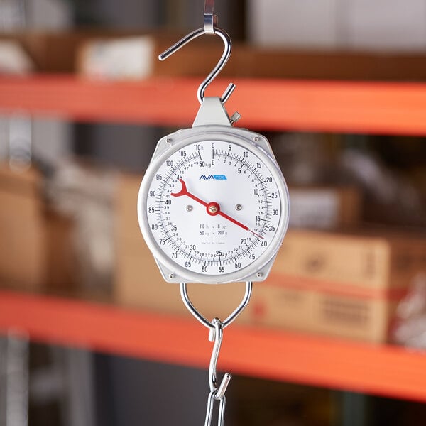 A round analog industrial hanging scale with a hook at the top and bottom for weighing items.