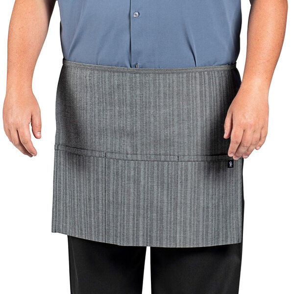 A man wearing a grey Uncommon Chef waist apron with pockets.