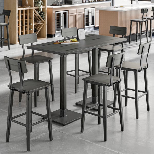 A Lancaster Table & Seating live edge bar height table with chairs in a room.