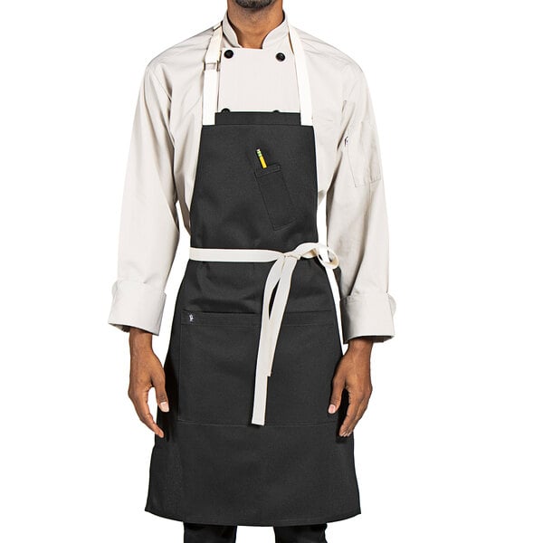 A man wearing a Uncommon Chef black apron with natural webbing.