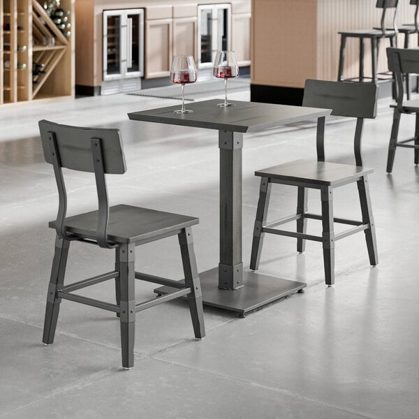 A Lancaster Table & Seating standard height table in slate gray with two chairs.