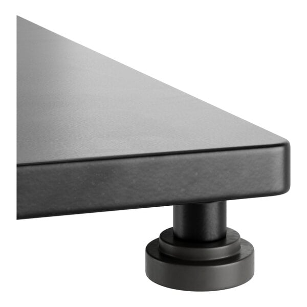 A close-up view of a slate gray solid wood table with a live edge and a sturdy round metal leg.