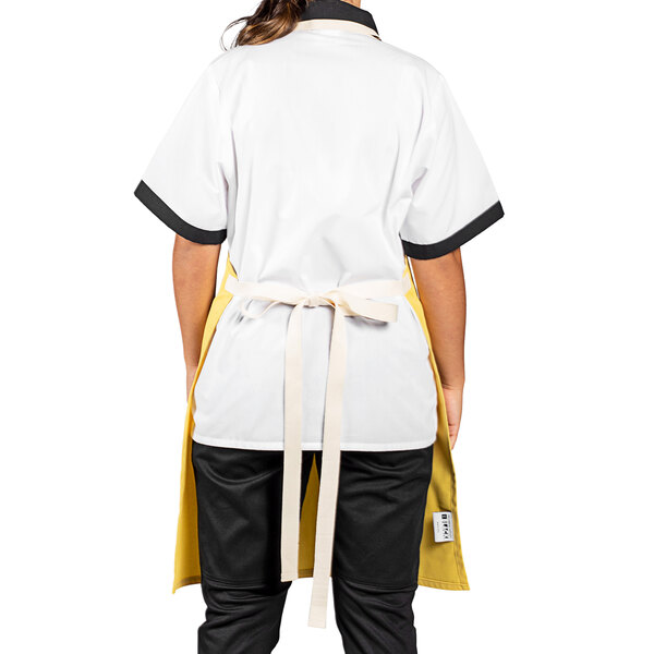 A woman wearing a white and yellow Uncommon Chef Avalanche Bib Apron with natural webbing.