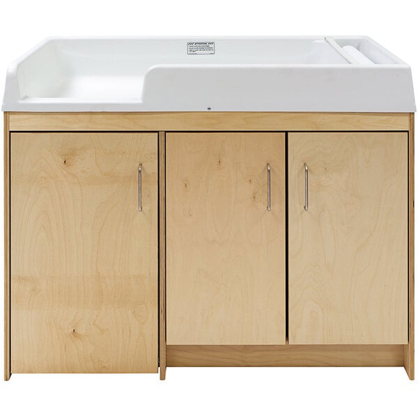 A natural birch plywood baby changing table with silver handles on a wooden cabinet.